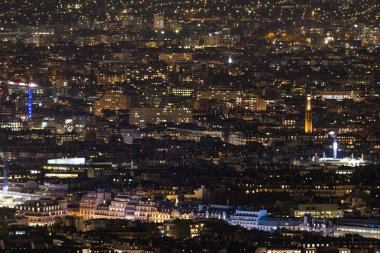 Aerial view of a sprawling cityscape illuminated by a tapestry of golden lights under a velvet sky, Paris, Ile-de-France, France.