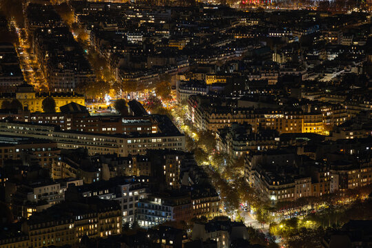 Aerial view of a sprawling cityscape ablaze with golden lights illuminating the streets and buildings, a nocturnal symphony of urban life, Paris, Ile-de-France, France.