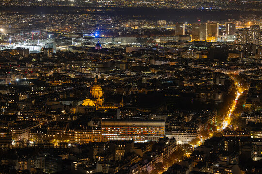 Aerial view of the illuminated D&ocirc;me des Invalides gleaming warmly amidst the dark urban tapestry under the night sky, Paris, Ile-de-France, France.