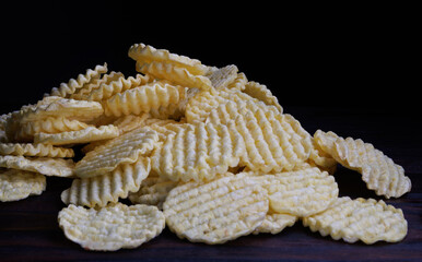 Round corn chips in a pile. Corrugated corn chips.