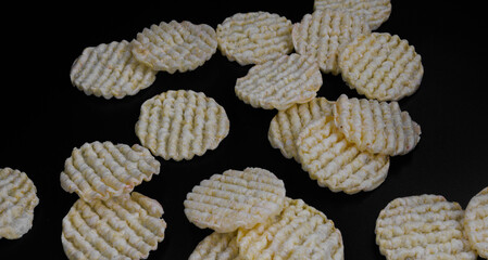 Round corn chips. Corrugated corn chips on a dark background.