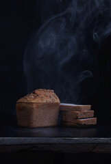 Half a loaf and pieces of sliced buckwheat bread on a black background. Steaming bread.