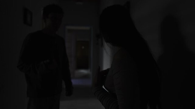 Man gaslighting his partner in a dark hallway, psychological manipulation and emotional control