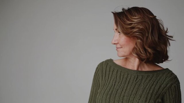 Portrait of a confident mature woman in a cozy pullover sweater against a neutral background