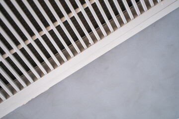Obraz premium Abstract low-angle shot of a white linear ventilation grille air vent set into a gray ceiling, creating a diagonal perspective