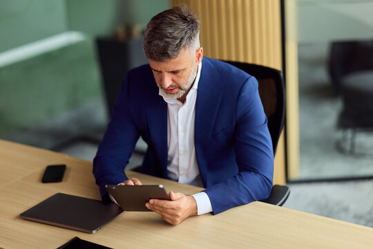 Professional Man In Blue Suit Using Tablet At Modern Office Desk - Powered by Adobe