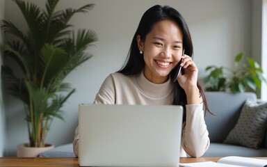 Smiling asian woman freelancer talking on phone and using laptop. High quality