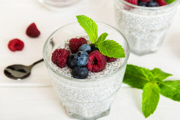 Healthy breakfast or morning with chia seeds vanilla pudding raspberry and blueberry berries on table background, vegetarian food, diet and health concept. Chia pudding with raspberry and blueberry