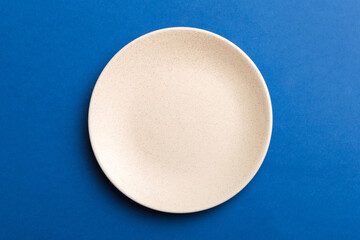 Top view of isolated of colored background empty round beige plate for food. Empty dish with space...