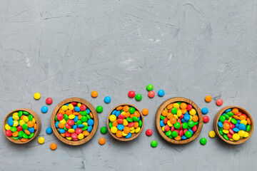 different colored round candy in bowl and jars. Top view of large variety sweets and candies with copy space