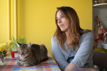 A woman with her cat friend at the table in the morning