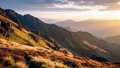 Sunlight bathes a rugged mountain landscape, highlighting the textures of grass-covered slopes and rocky outcrops under a cloudy sky.