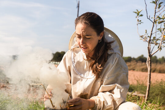 Female Beekeeper Preparing Smoker in Rural Apiary Field