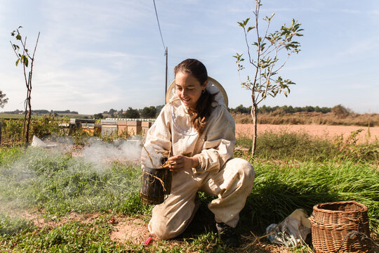 Female Beekeeper Preparing Smoker in Rural Apiary Field