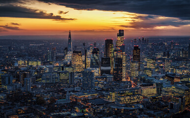 Aerial view of the illuminated City of London cluster, financial hub with office skyscrapers, during dusk