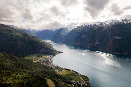 Aerial view of the serene fjord reflecting the sky, nestled between towering mountains with snow-capped peaks, Aurlandsfjord, Aurland, Vestland, Norway.