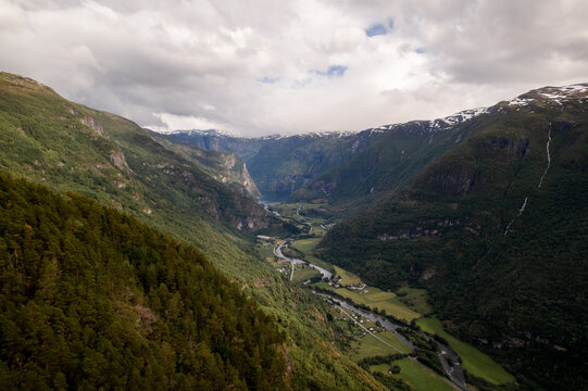 Aerial view of a dramatic valley with lush green slopes meeting the sky under a blanket of clouds, Aurland, Vestland, Norway.