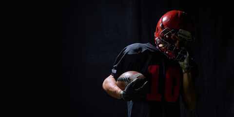 American football player holding ball with emotional fatigue in dramatic low light. Concept of recovery education, mindset training, editorial sport content, branding materials.
