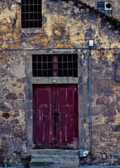 An old building with a red door and barred windows.