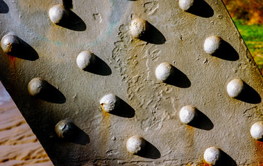 Close-up of a metal surface with rivets, showing texture and shadows.