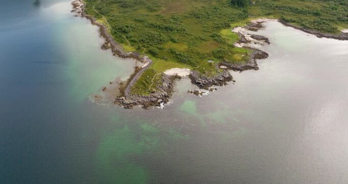 Rocky coastline and clear turquoise water, &Aring;rnessan, Stokmarknes, Norway. Aerial drone top-down orbiting