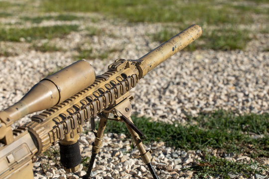 Airsoft sniper rifle in camouflage on a training field
