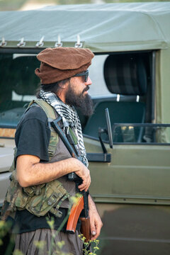 Man in military gear with vintage vehicle in background