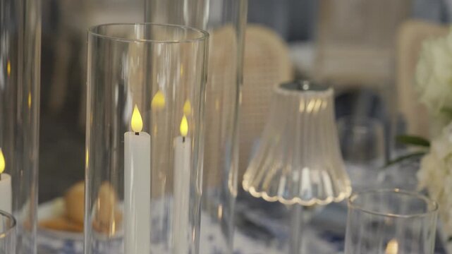 Twinkling LED candle lights in glassware vases on wedding banquet table setting