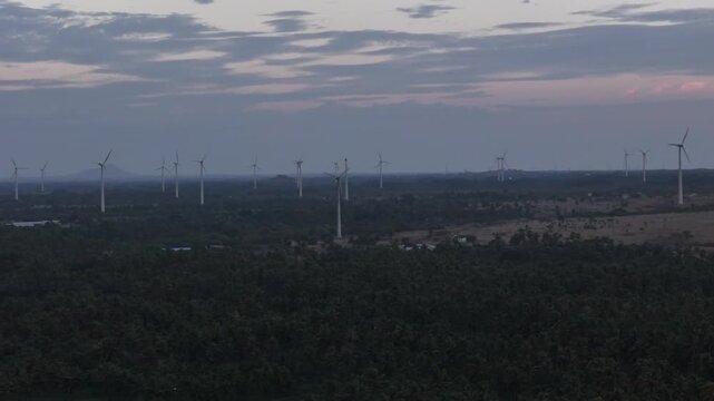 Aerial view of towering wind turbines against a backdrop of fertile agricultural land represents the intersection of ecology, technology, and rural power generation.