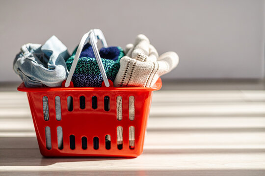 Clothing items in a red basket on a bright wooden floor