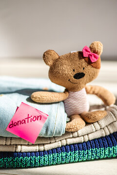 Teddy bear with clothes and donation note on table