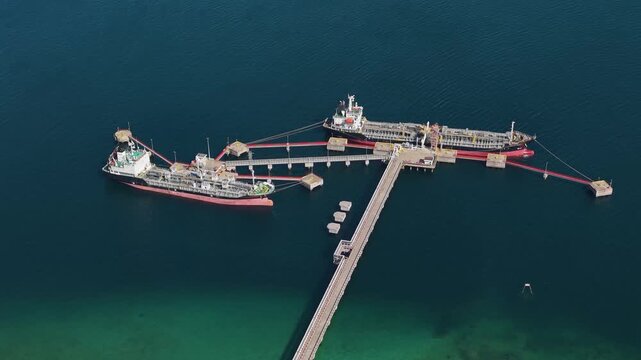 Slow drone shot of petrochemical tankers docked at Labuan port, Malaysia, showing industrial export terminal and methanol shipping operations over the deep blue sea.
