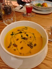 Creamy pumpkin soup with herds, sour cream, and balsamic drops served in a stylish bowl. 