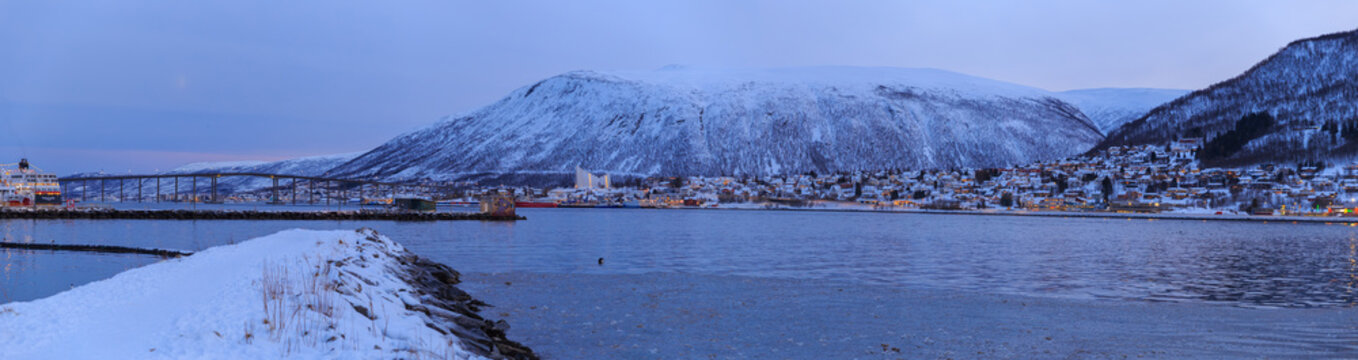 panoramic view of Tromso bay area, cityscape with snow mountain in the background  at blue hour, polar night