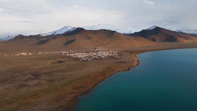 drone approach Karakul village on the shore of Lake Karakul, Pamir Mountains, Tajikistan high angle aerial