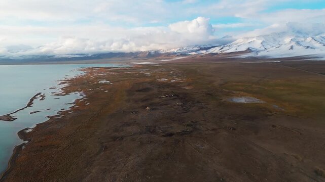 Aerial view of Karakul lake and Pamir Mountains peaks covered in snow, Tajikistanremote wilderness drone footage
