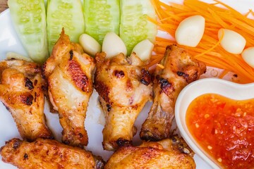Delicious grilled chicken wings with fresh vegetable garnish and dipping sauce