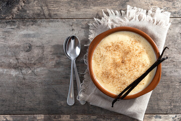 Creamy homemade Spanish custard served in a bowl on wooden table. Top view. Copy space