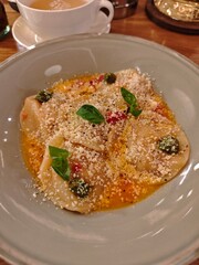 Fresh ravioli served in a rich buttery sauce with basil, pesto dots, and grated cheese. Elegant Italian-style dish with warm colors and refined restaurant presentation. 