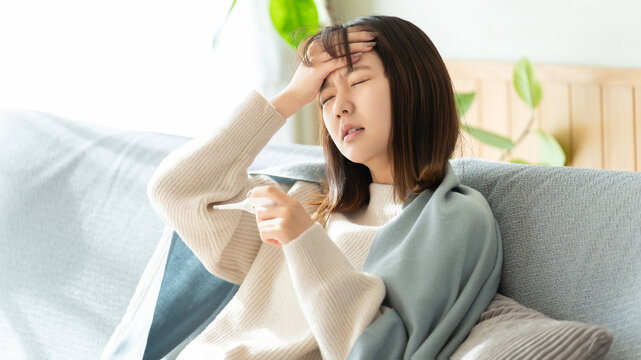 熱を測る体調不良の女性