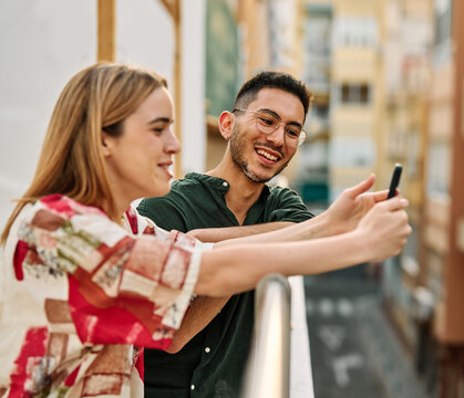 Portrait of a young happy couple having fun taking a selfie with camera on smartphone outdoors. Girlfriend and boyfriend bonding, love concept during summer. - Powered by Adobe