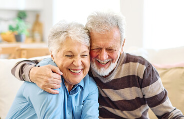 Portrait of an elderly senior couple having breakfast and looking at a laptop at home. Happy healthy affectionate senior couple eating and sitting at kitchen table having fun enjoying morning meal tog