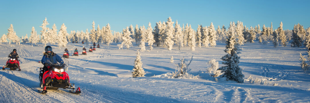 Group of snowmobiles in snowy panoramic landscape, Lapland panorama near Saariselka in winter, Finland travel header