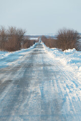 Scenic winter road covered in glistening snow leading through rural landscape, perfect for travel, adventure, or peaceful getaway concepts