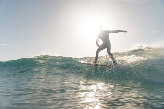 Surfer riding a wave against the sun in Morocco