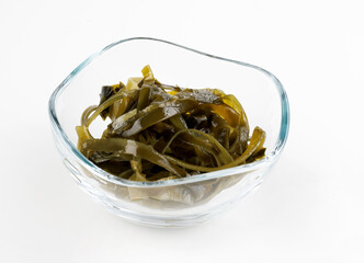 Seaweed salad in a glass cup on a white background.