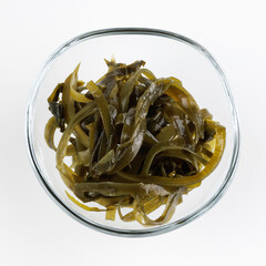 Seaweed salad in a glass cup on a white background.