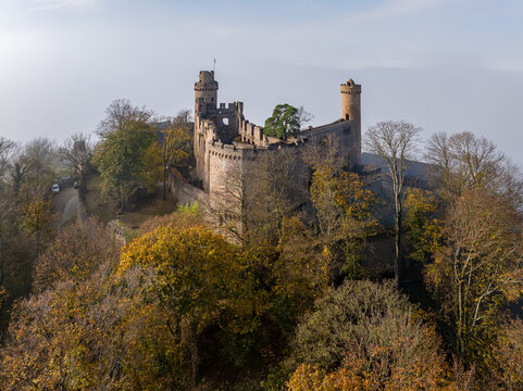 Aerial view of the Castle Auerbach ruins perched atop a hill, blending with the autumn foliage, a medieval fortress against a backdrop of soft, misty light, Bensheim, Hessen, Germany.
