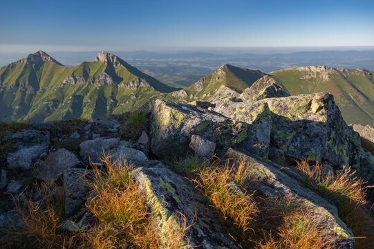 Aerial view of the rugged, sun-kissed peaks of Jahnaci stit rise majestically against a serene, hazy horizon, Vysoke Tatry, Presov Region, Slovakia.