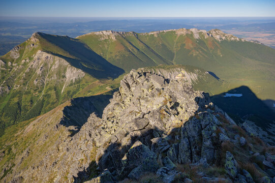 Aerial view of the rugged, sun-kissed Jahnaci stit peak, a rocky outcrop piercing the sky with verdant slopes cascading below, Vysoke Tatry, Presov Region, Slovakia.